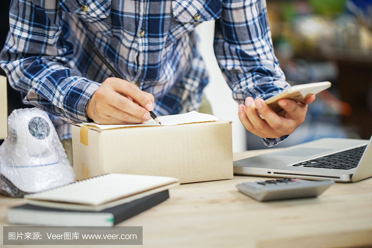 年輕的創(chuàng)業(yè)小企業(yè)主在工作場所的盒子里裝攝像頭閉路電視。自由職業(yè)者銷售者準備產(chǎn)品的包裝過程在家里。網(wǎng)絡(luò)銷售,網(wǎng)絡(luò)營銷,